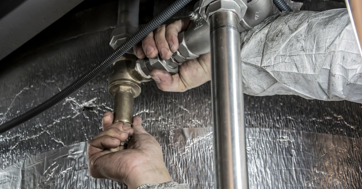 Plumber repairing a pipe under a kitchen sink