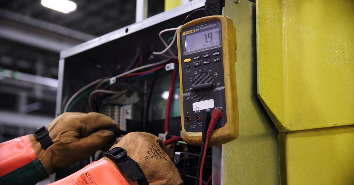 Electrician working on a wiring panel with tools