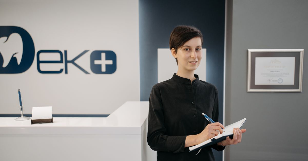 Friendly human receptionist greeting a visitor at an office front desk
