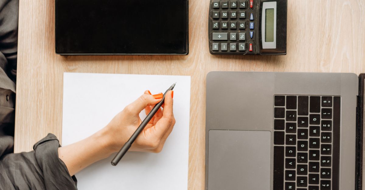 Business owner comparing options on a laptop with a calculator