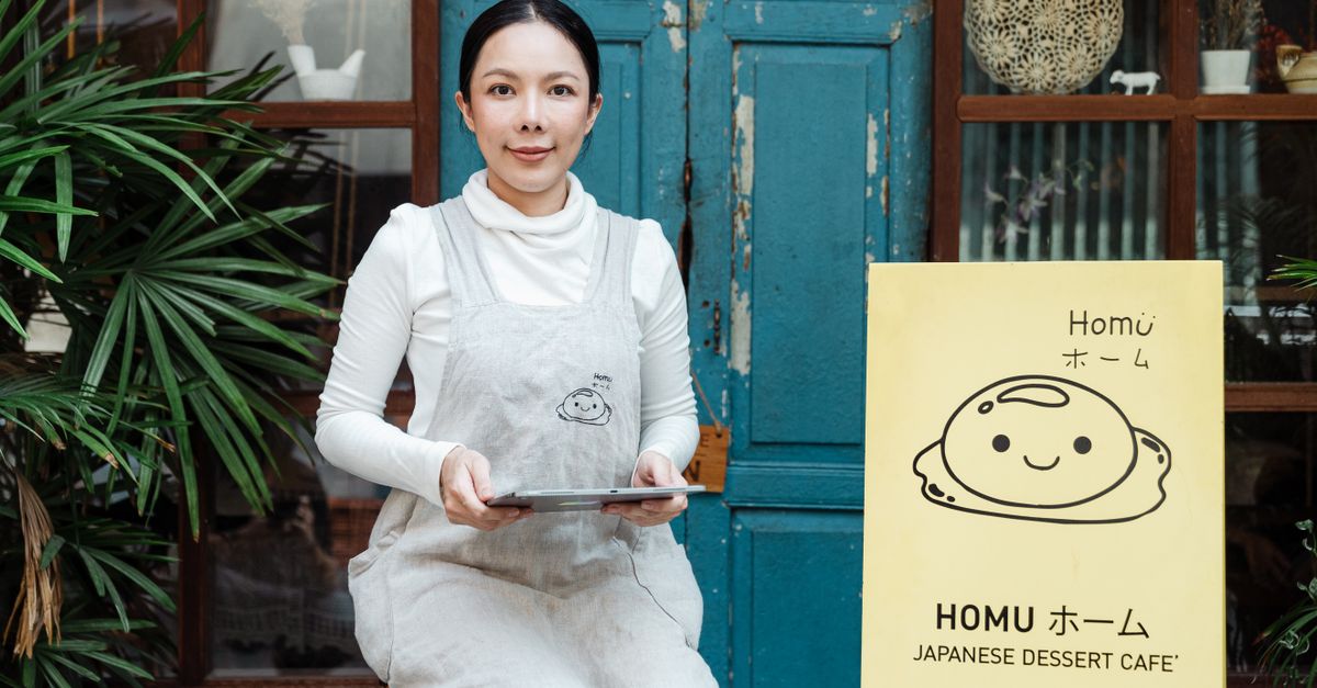 Owner of a small cafe talking on the phone with a tablet