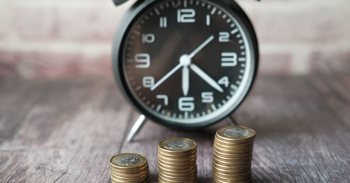 Stacks of coins next to a small clock representing cost over time