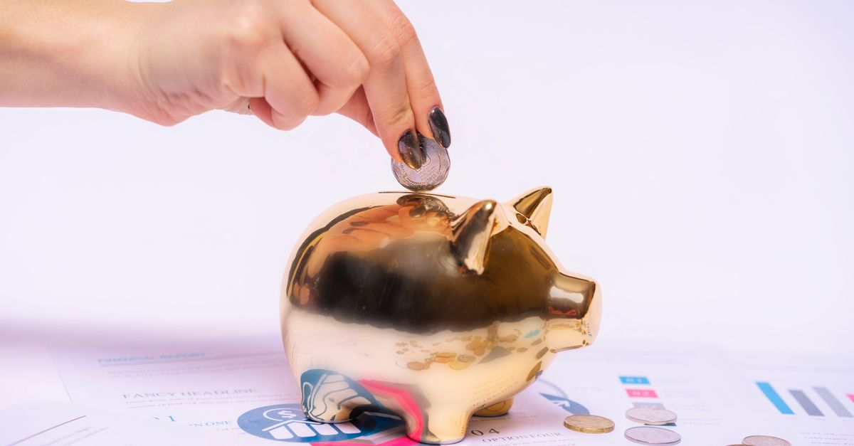 Hand putting a coin into a piggy bank to show savings