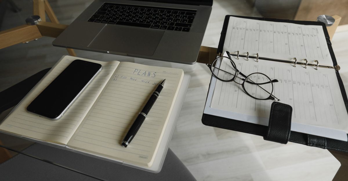 Organized desk with a phone, planner, and laptop