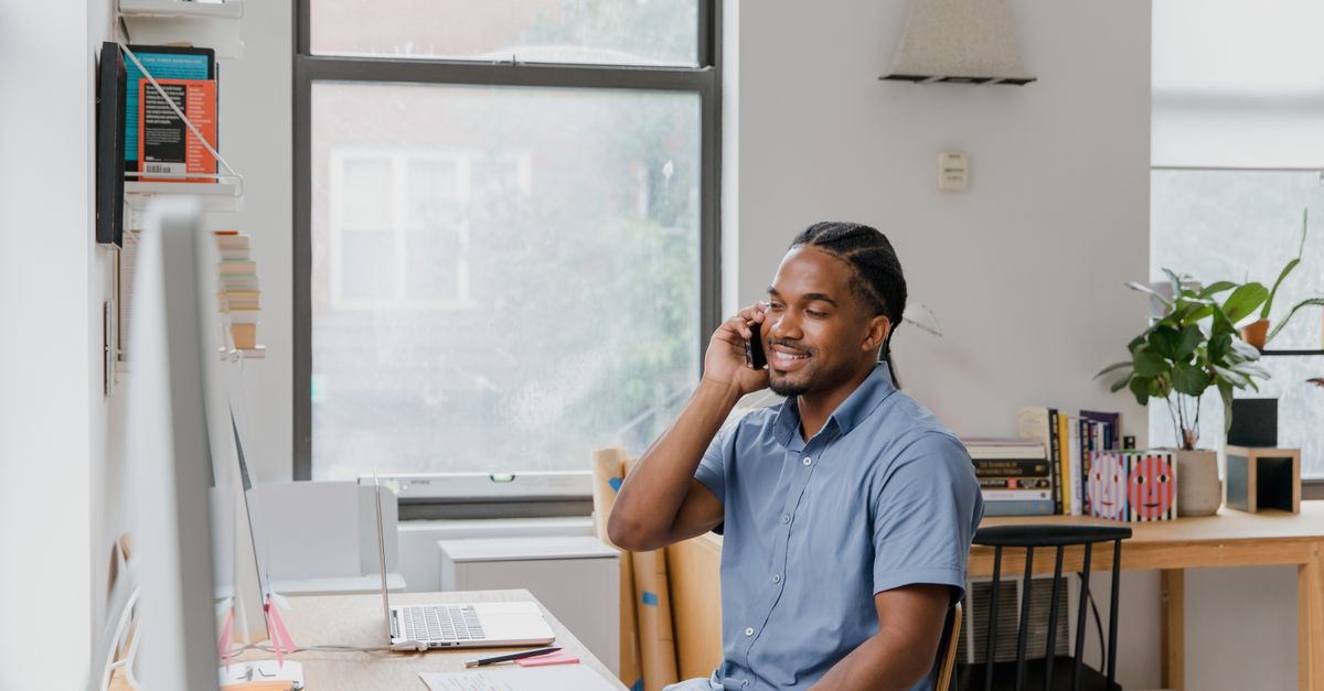 Small business owner taking a phone call while working on a laptop