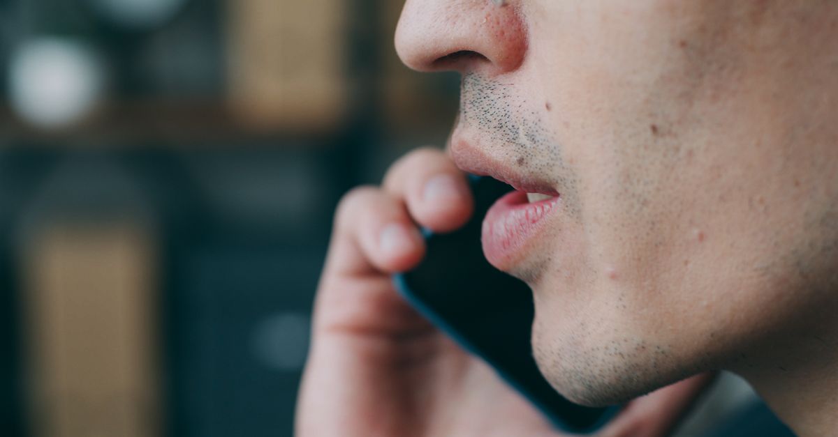 Person speaking into a smartphone with a voice assistant